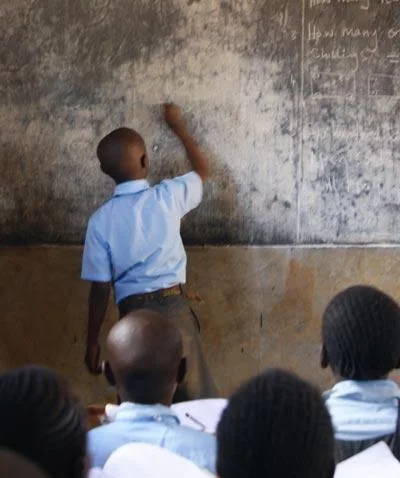 Schoolboy wriitng on blackboard in Africa